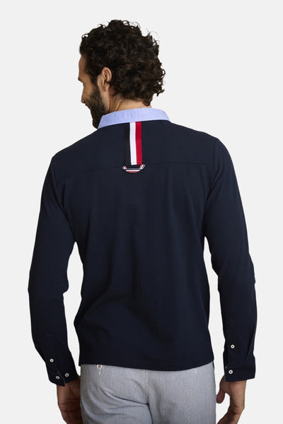 Polo bleu marine DELAHAYE, à manches longues, avec bande tricolore et empiècement au dos, porté avec un pantalon rayé.
