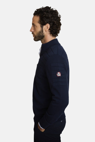 Gilet bleu de DELAHAYE, en maille texturée avec détail de patch logo sur la manche, vue de côté.
