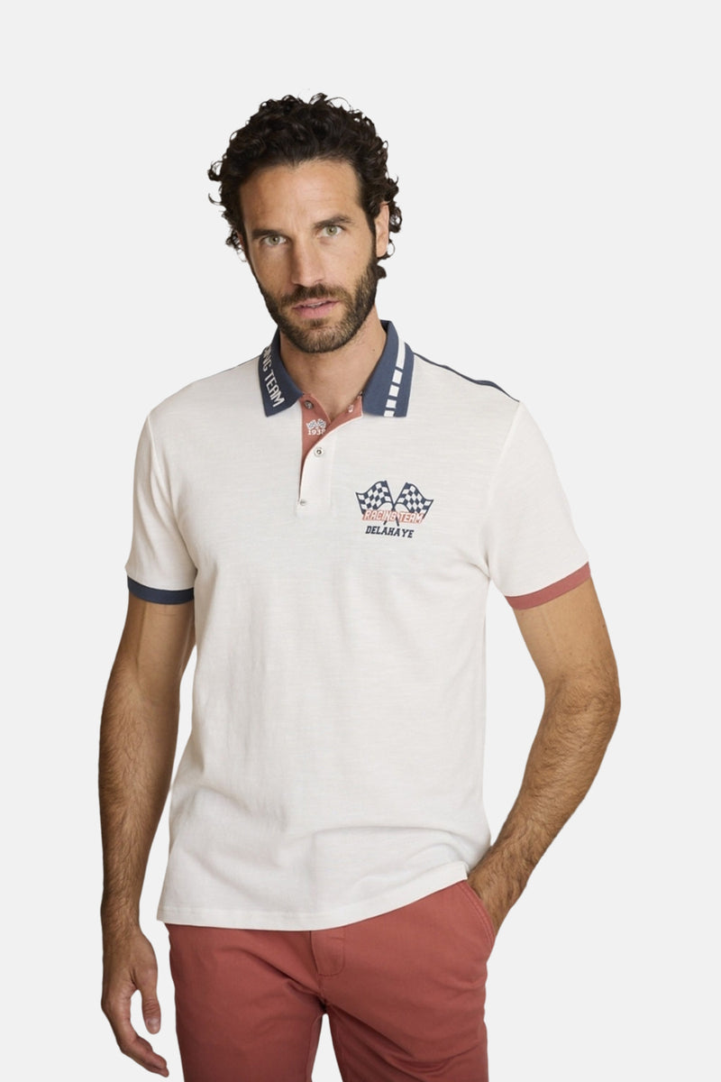 Polo écru à manches courtes de DELAHAYE, col et manches contrastés, motif imprimé sur la poitrine, porté avec un pantalon rouge.
