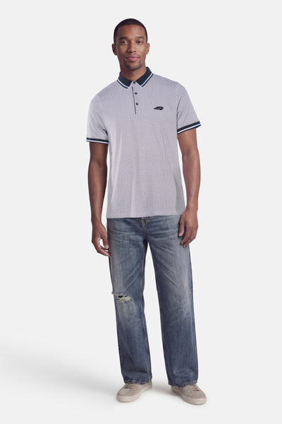 Polo brun de DELAHAYE, à motifs géométriques, porté avec un jean ample déchiré et des baskets grises.