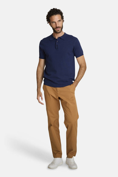 T-shirt bleu à manches courtes de DELAHAYE, motif texturé, porté avec un pantalon marron et des chaussures blanches.