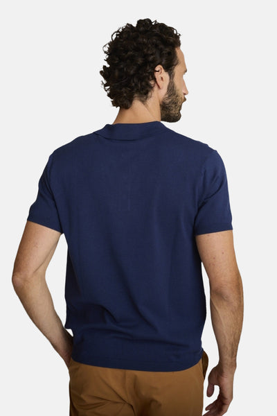 T-shirt bleu à manches courtes de DELAHAYE, porté avec un pantalon marron clair, vu de dos.