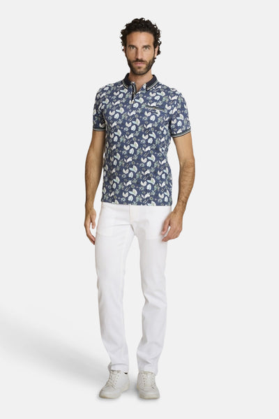 Polo bleu par DELAHAYE, avec un motif floral, porté avec un pantalon blanc et des baskets blanches.