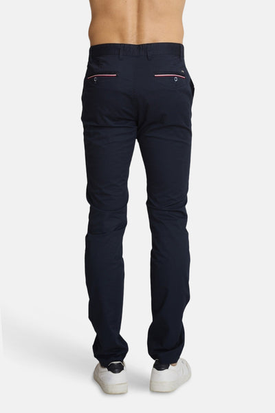 Chino bleu marine de DELAHAYE, avec passepoils roses sur les poches arrière, porté avec des baskets blanches.