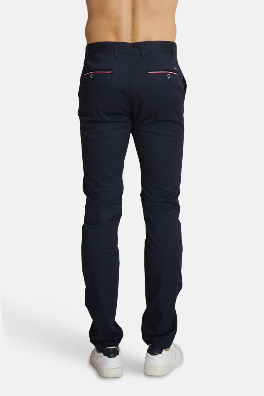Chino bleu marine de DELAHAYE, avec passepoils roses sur les poches arrière, porté avec des baskets blanches.