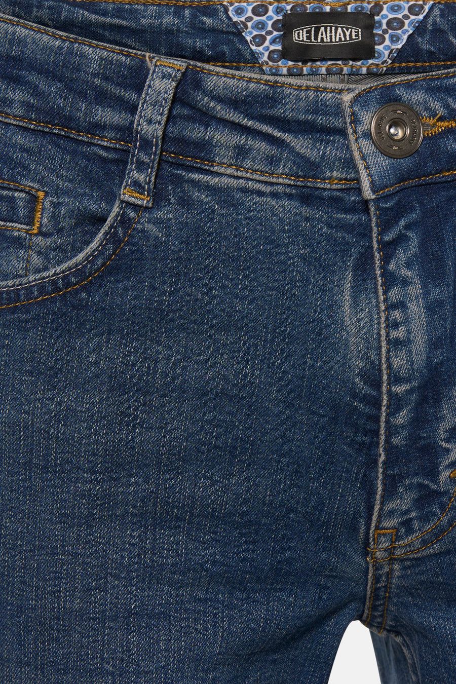 Jean droit bleu par DELAHAYE avec détail de couture apparente et doublure à motifs circulaires.

