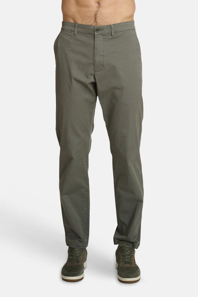 Olive green slim-fit joggers by DELAHAYE, front view, with button fly and cuffed hems, worn with dark green sneakers.