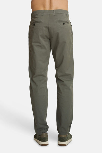 Olive green jogging pants by DELAHAYE, back view, slim fit with buttoned back pockets and elasticated cuffs, worn with dark green suede sneakers.
