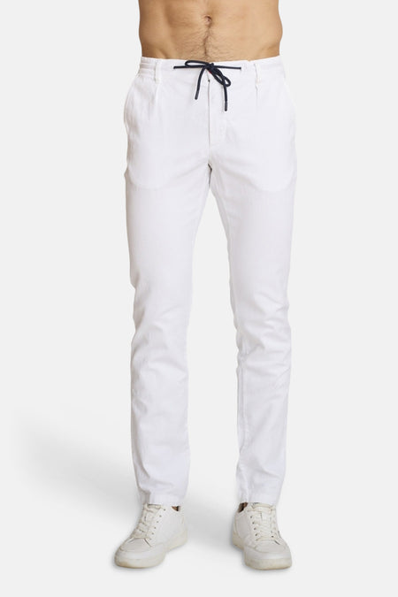 Chino blanc de DELAHAYE, avec cordon de serrage à la taille et chaussures de sport blanches.