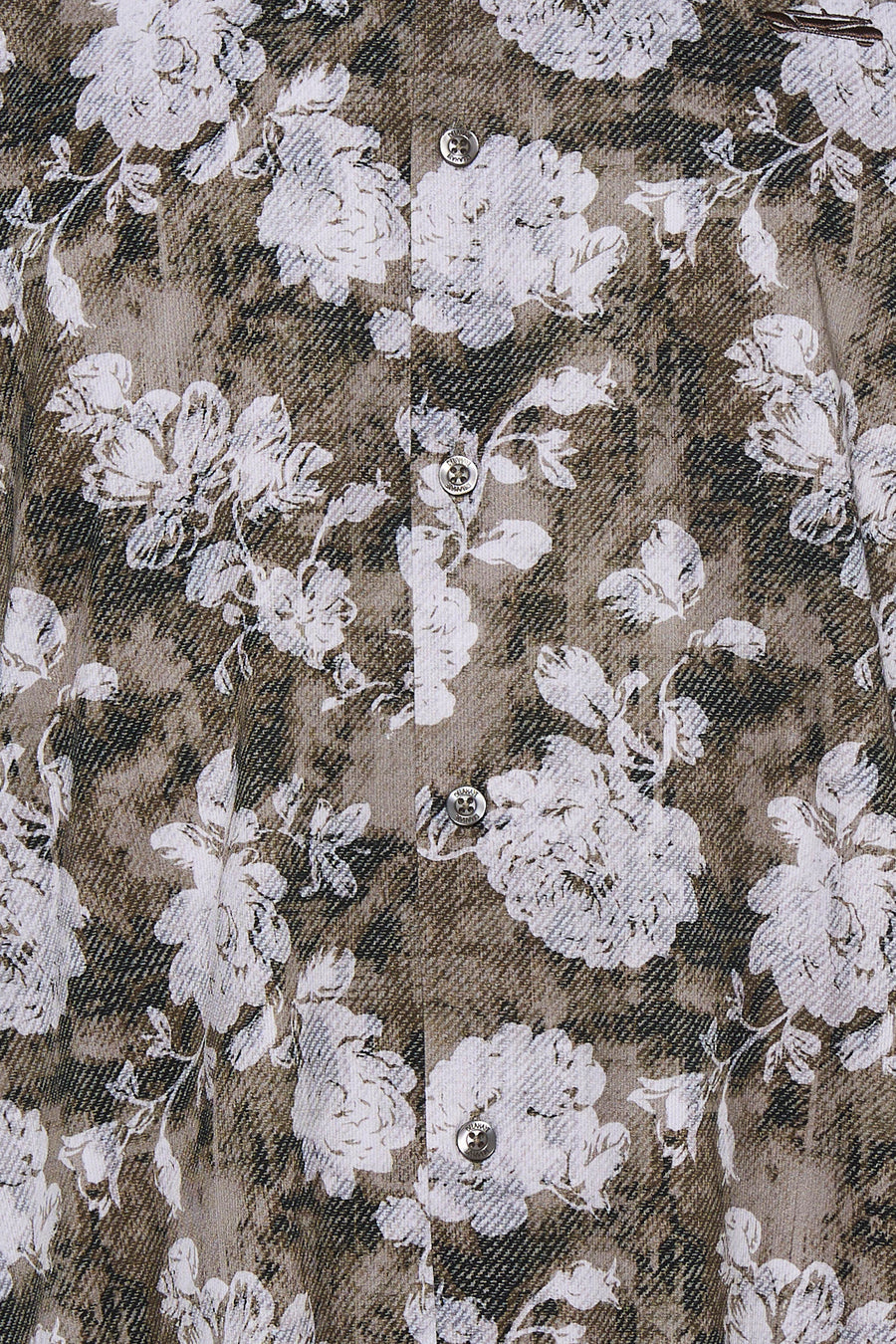 Multicolored long-sleeve blouse with white floral pattern on brown and black textured fabric, featuring silver buttons down the front, close-up view