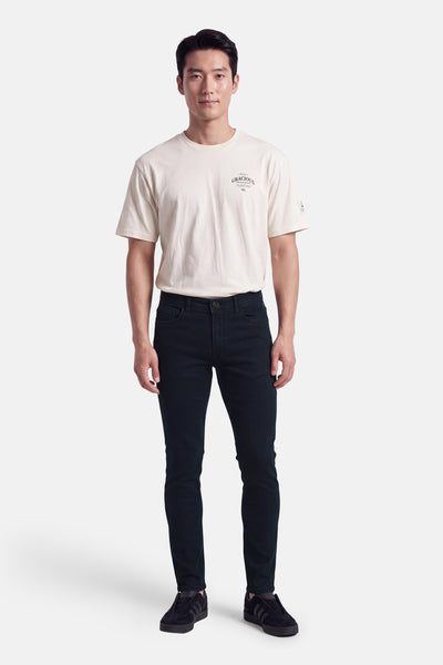 Chino bleu ajusté par DELAHAYE, porté avec t-shirt blanc et baskets noires, vue de face.