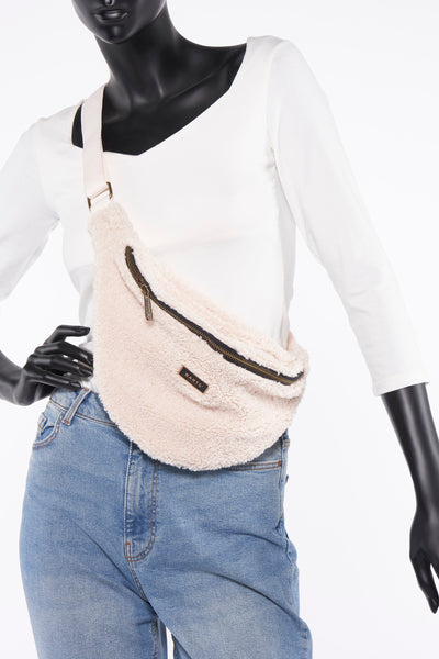 Sac banane en fausse fourrure écru de BARTS, porté sur un mannequin avec un jean bleu et un haut blanc.
