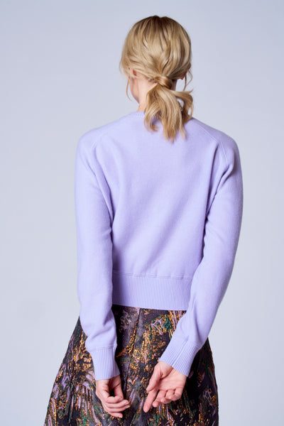 Gilet violet de TERRE BLEUE, dos visible, porté avec une jupe à motif floral.