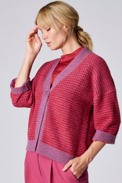 Gilet violet par TERRE BLEUE avec une texture tricotée, porté sur un chemisier rouge.