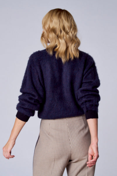 Gilet bleu de TERRE BLEUE, à manches longues, porté avec un pantalon à carreaux et à taille haute.