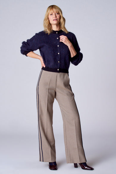 Gilet bleu de TERRE BLEUE, porté avec un pantalon à carreaux à rayures et des chaussures bordeaux à talons.