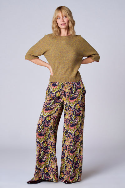 Pull vert par TERRE BLEUE, à manches courtes et porté avec un pantalon à motif floral.
