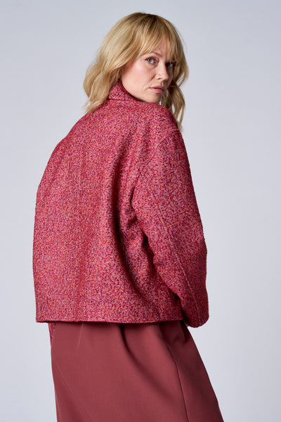 Veste courte rouge de TERRE BLEUE, à texture tweedée, portée avec une jupe rouge.