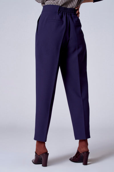 Short bleu de TERRE BLEUE, coupe droite et taille haute élastiquée, porté avec des chaussures à talons et des chaussettes marron.