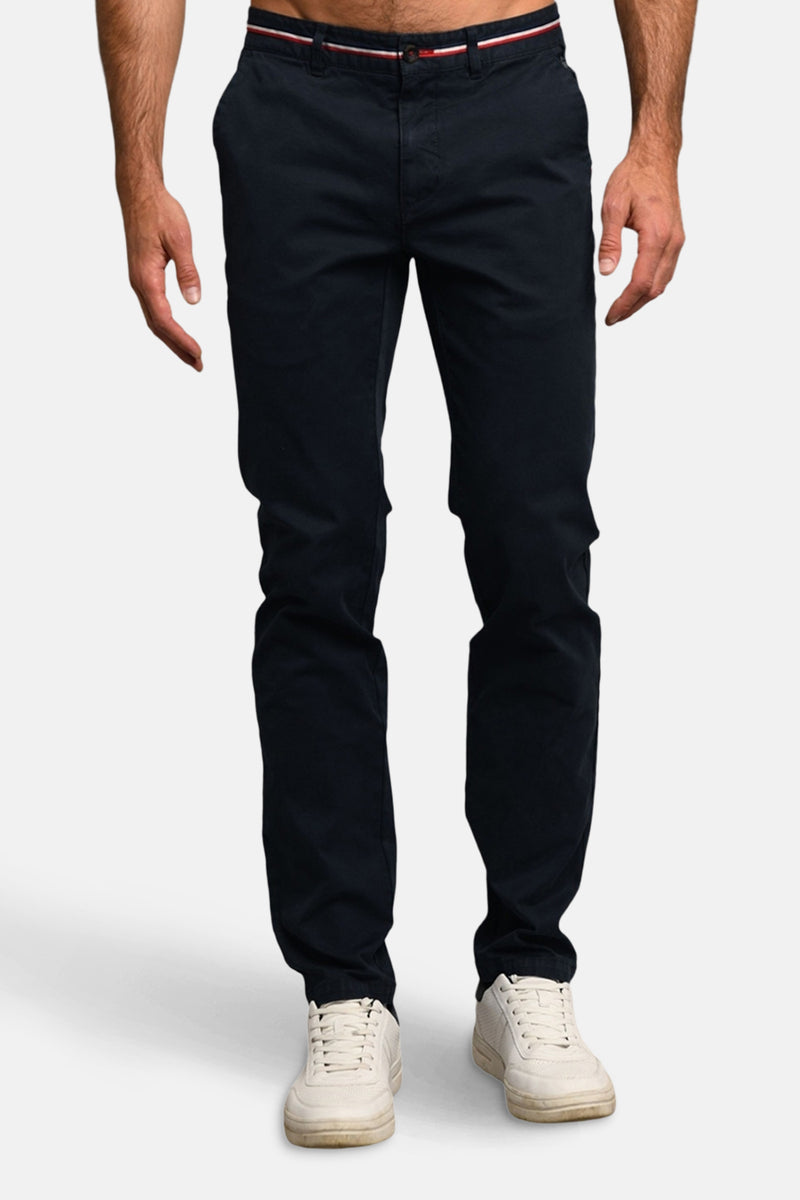 Blauwe broek van DELAHAYE met rood-wit gestreepte riem, gedragen met witte sneakers.