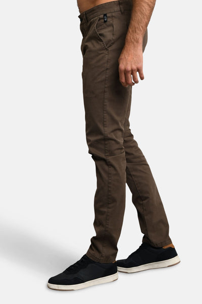 Pantalon marron de DELAHAYE, coupe chino, porté avec des chaussures de sport noires à semelles blanches, en vue latérale.