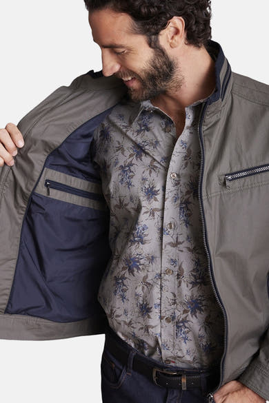 Veste courte verte de DELAHAYE avec poches zippées et doublure intérieure bleu marine, portée sur une chemise à motifs floraux.