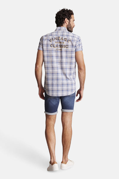 Blauwe geruite blouse met lange mouwen van DELAHAYE, met opschrift op de rug en gedragen met een spijkerbroekshort.