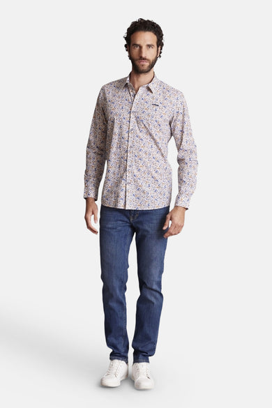 Chemise multicolore de DELAHAYE, avec un motif fleuri, portée avec un jean et des chaussures blanches.