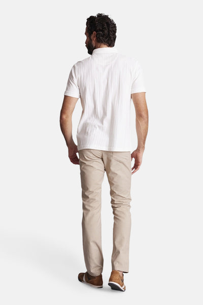 Polo écru texturé de DELAHAYE, porté avec un pantalon beige et des chaussures marron, vue de dos.
