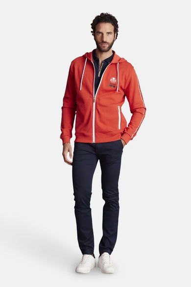 Blauwe broek van DELAHAYE, gedragen met een marineblauw poloshirt en een oranje hoodie.