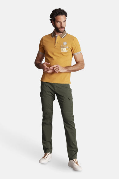 DELAHAYE groene bermuda, gedragen met een mosterdgele polo en witte sportschoenen met bruine veters.
