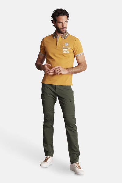 DELAHAYE groene bermuda, gedragen met een mosterdgele polo en witte sportschoenen met bruine veters.