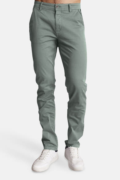 Pantalon vert de DELAHAYE, coupe ajustée, porté avec des chaussures de sport blanches.