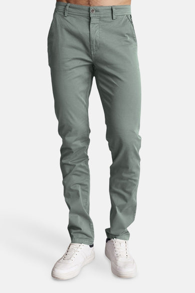 Pantalon vert de DELAHAYE, coupe ajustée, porté avec des chaussures de sport blanches.