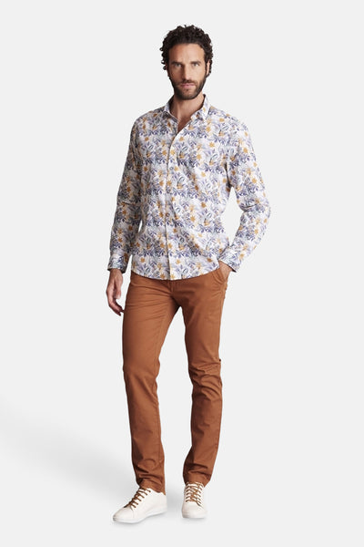 Bruine chino van DELAHAYE, gedragen met een bloemenoverhemd en witte sneakers.