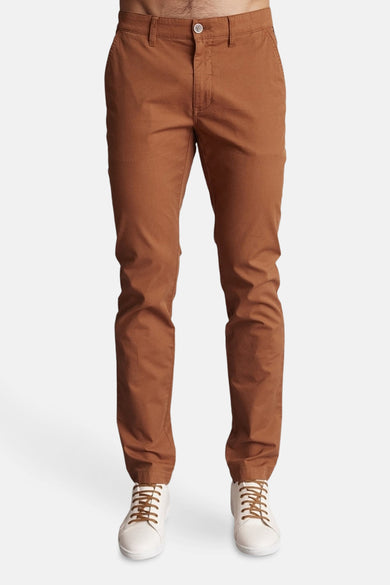 Bruine chino van DELAHAYE, gedragen met witte sportschoenen met bruine veters.