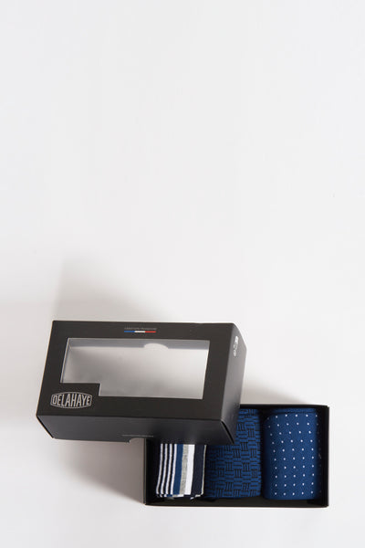 Coffret de chaussettes bleues par DELAHAYE, avec motifs à rayures, géométriques et à pois, présentées dans une boîte noire ouverte.
