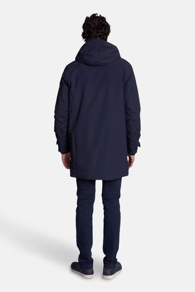 Veste longue bleue de DELAHAYE, vue de dos, portée avec un jean et des chaussures sombres.