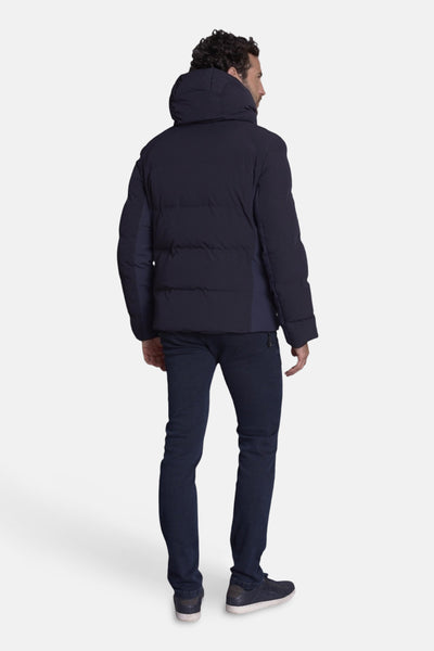 Veste courte bleue de DELAHAYE, avec capuche et fermeture éclair, vue de dos, portée avec un pantalon et des chaussures bleus.