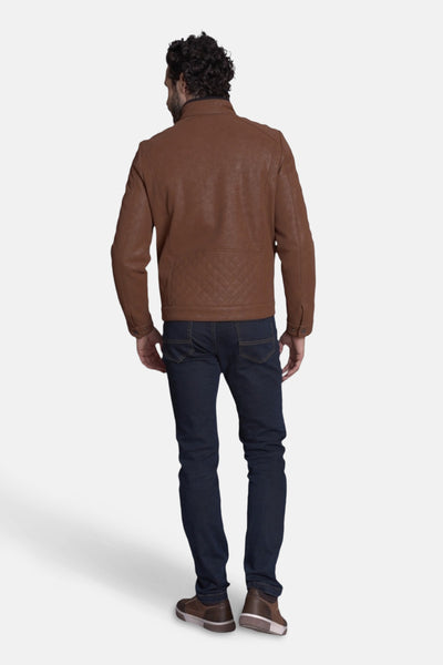 Veste courte brune par DELAHAYE avec motif matelassé au bas du dos, portée avec un jean bleu foncé et des chaussures marron.