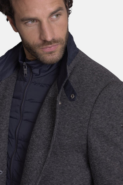 Veste longue grise de DELAHAYE, portée sur un gilet bleu marine matelassé.