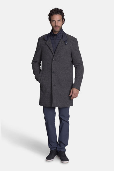 Lange grijze jas van DELAHAYE, gedragen met een marineblauwe gilet en een bijpassende broek.