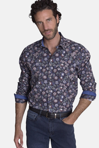 Chemise bleue à motifs floraux de DELAHAYE, avec col et revers de manches bleus et porté avec un jean bleu et une ceinture noire.