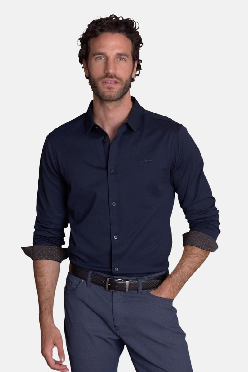 Navy blue button-down chemise with contrast polka dot cuffs, worn by model with dark belt and trousers, front view