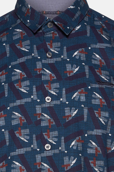 Chemise bleue par DELAHAYE avec motif géométrique complexe et boutons apparents.
