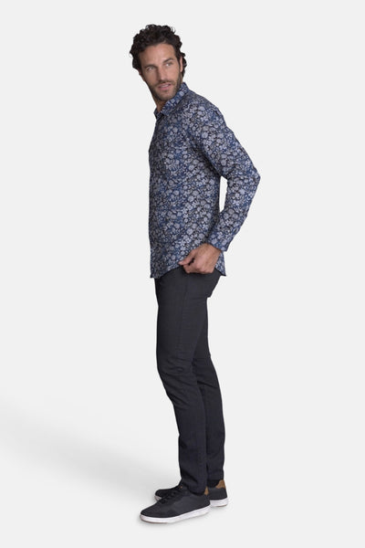 Chemise bleue à motifs floraux de DELAHAYE, portée avec un pantalon foncé et des baskets.