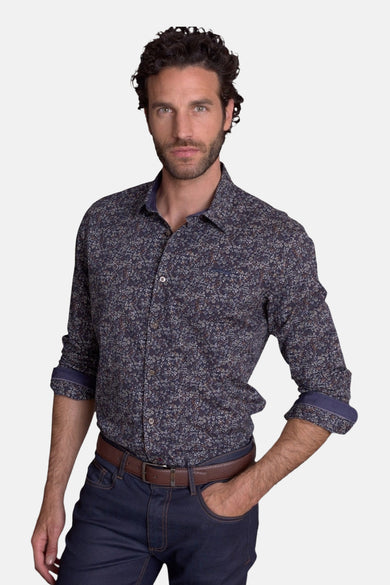 Blue patterned long-sleeve chemise with floral print, rolled cuffs, and button-down front, worn with dark jeans and brown belt in lifestyle pose.