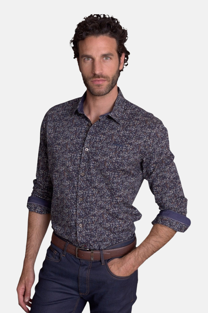 Blue patterned long-sleeve chemise with floral print, rolled cuffs, and button-down front, worn with dark jeans and brown belt in lifestyle pose.