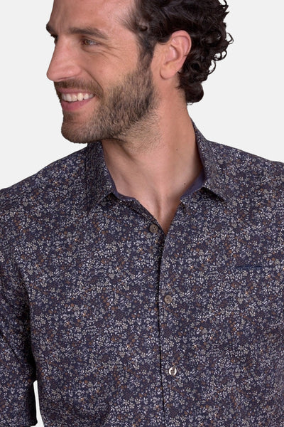 Blue floral-patterned men's chemise with button-down front, chest pocket, and classic collar, shown in close-up side view.