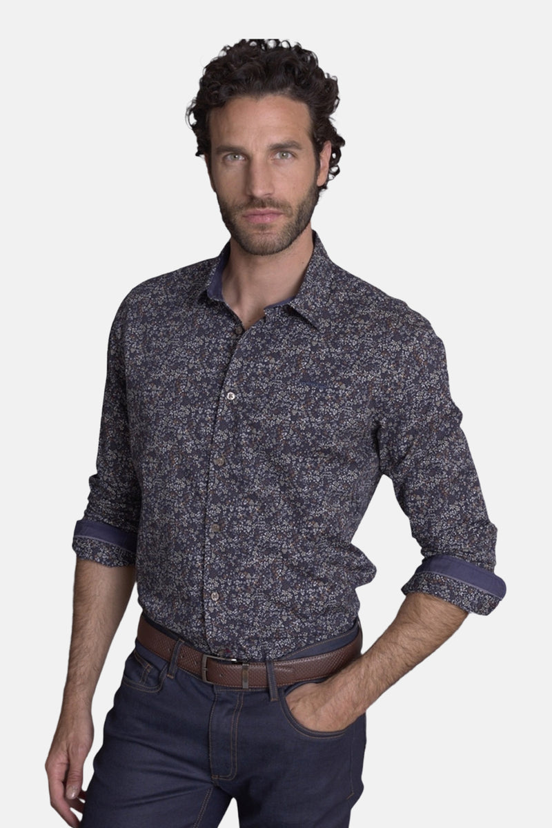 Chemise bleue à motifs floraux de DELAHAYE, avec col et poignets contrastés, portée avec un jean et une ceinture marron.